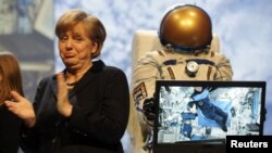 Германия канцлери Ангела Меркель космос менен түз байланыш учурунда европалык астронавт Андрэ Кюперстин сөзүн угууда. Гановердеги көргөзмөдө. 5-март 2012