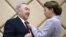 Дарига Назарбаева, спикер сената парламента, прикрепляет к лацкану пиджака своего отца Нурсултана Назарбаева нагрудный знак «Почётный сенатор». Нур-Султан, 6 июня 2019 года.  