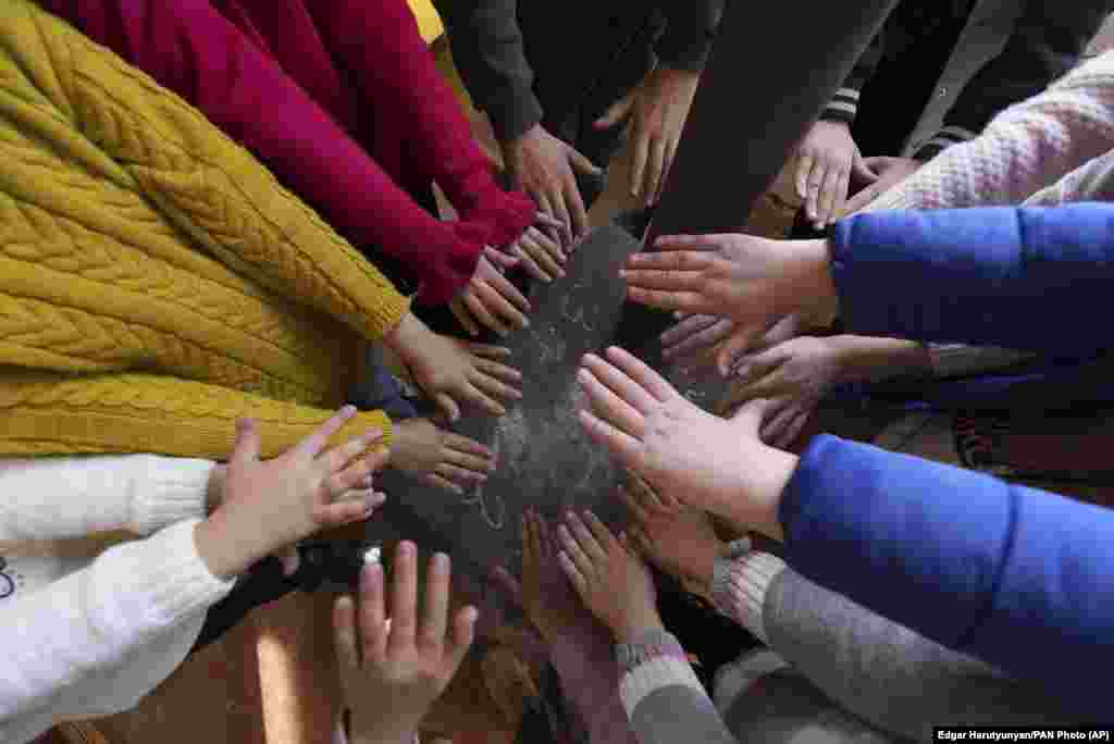 Schoolchildren warm themselves around a stove in their classroom in Stepanakert. &nbsp;