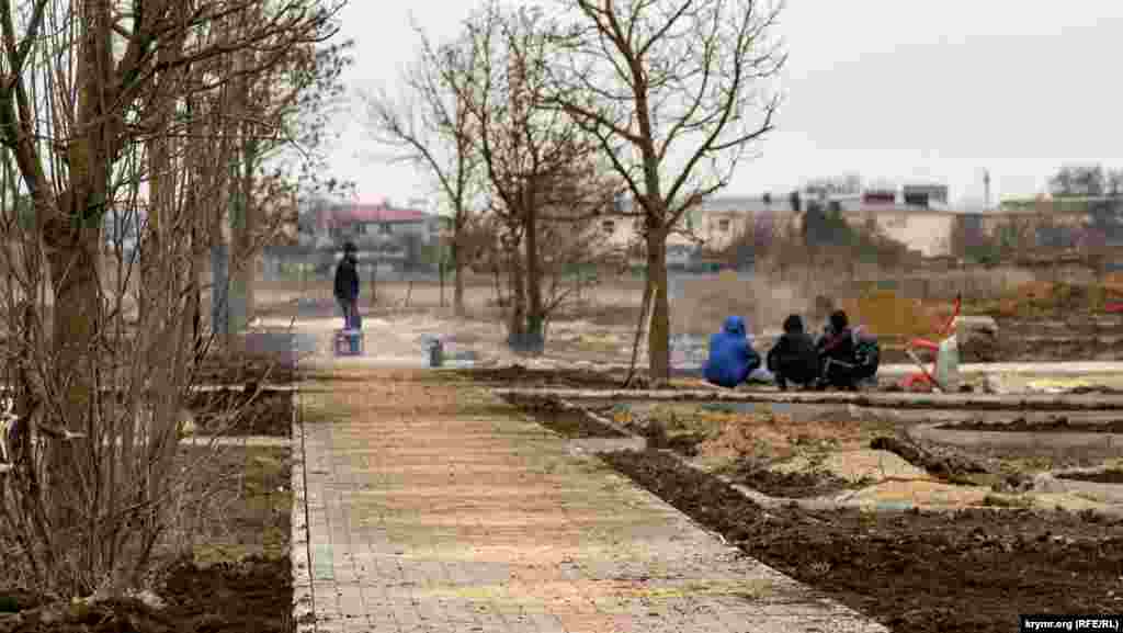 Рабочие, задейсвованные в капремонте на средства правительства Москвы территории общего пользования, вместе с местными мальчишками греются у костра