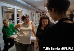 Українки, які працюють в салоні у Празі, оглядають костюм, який вони пошили