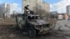 A soldier examines a destroyed Russian infantry mobility vehicle after a fight in Kharkiv on February 27.