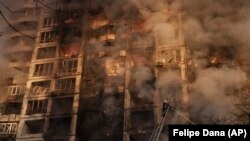 Пожарные тушат огонь в жилом доме после обстрела в Киеве 15 марта