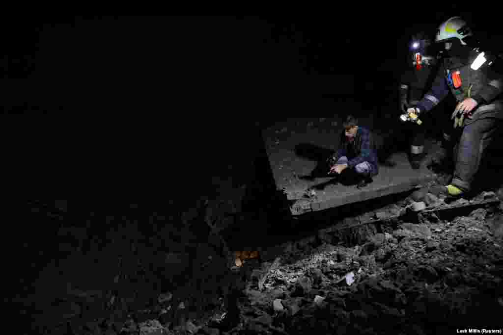 Пожежники посеред ночі перевіряють місце обстрілу, де утворилася велика вирва. На щастя, обійшлося без жертв. Харків, 30 червня 2022 року