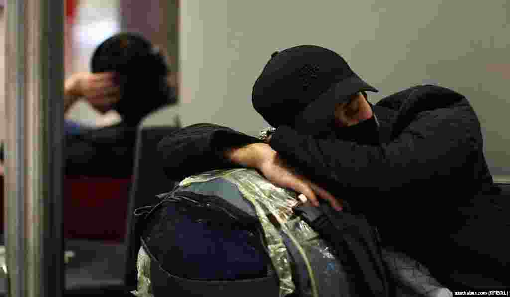 Uklap ýatan ýigidiň başyndaky papakda &quot;Täze döwür&quot; diýlen ýazgy bar.