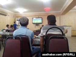 Türkmenistanda kafede telewizora tomaşa edýän adamlar