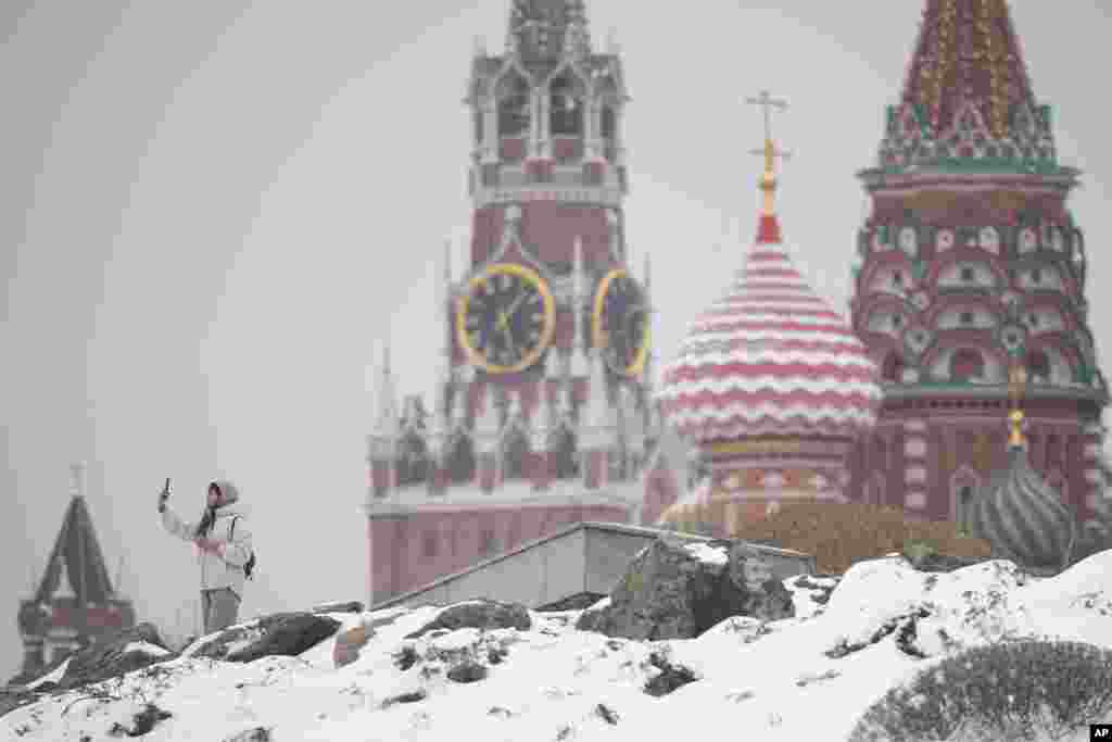 Мәскәүдә кар явып узганнан соң бер хатын Кремль һәм Василий Блаженный чиркәве фонында үз-үзен фотога төшерә.