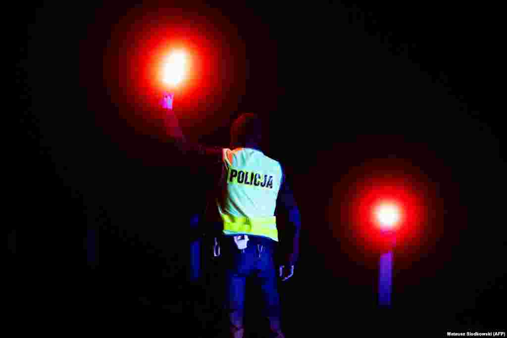 A police officer holds up lights at a checkpoint near the village of Bialowieza, in eastern Poland, close to the Polish-Belarusian border. Poland has declared a state of emergency in the area and only residents are allowed to enter.