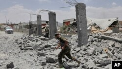 یک سرباز حوثی‌های یمن در حال عبور از ویرانه‌ای در صنعا که گفته می‌شود هدف حمله ارتش آمریکا قرار گرفته است 