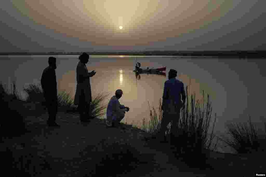 مردم محلی در حال تماشای صیادانی که تورهای ماهیگیری خود را به رودخانه چناب در ملتان، پاکستان، می‌اندازند