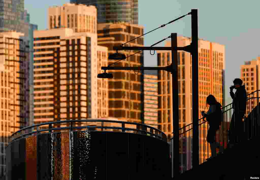 Люди прогуливаются по новоотстроенной набережной реки Москвы с видом на небоскрёбы. REUTERS/Maxim Shemetov.