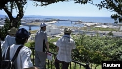 Японски граждани наблюдават бреговата лини от височината на парк в Ишиномаги, префектура Мияги