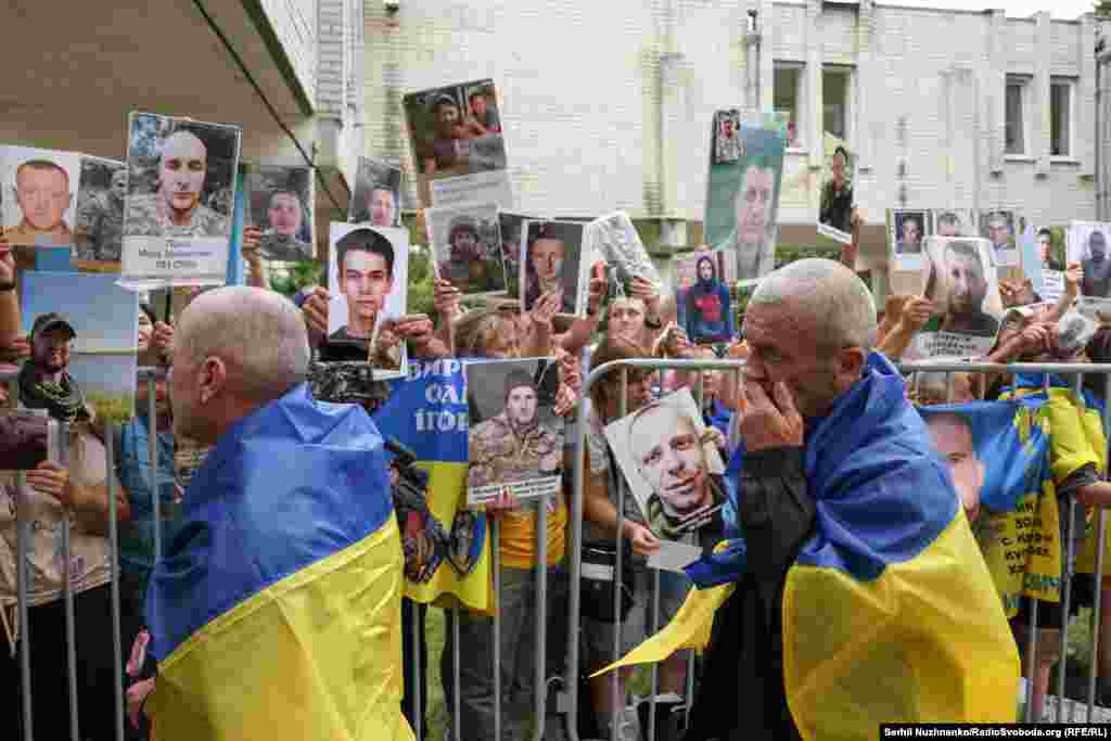 Українські військові, які повернулися з російського полону, дивляться на портрети зниклих безвісти