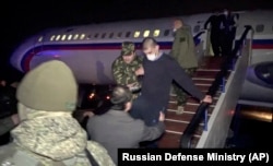 Азербайжан бийлиги боштондукка чыгарган армян туткуну Еревандын аба майданындагы орусиялык аскер учактан түшүүдө. Армения. 2020-жылдын 14-декабры.