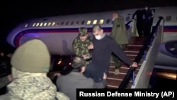 ARMENIA -- An Armenian captive, wearing a face mask to curb the spread of COVID-19, is escorted off a Russian military plane upon arrival at a military airport outside Yerevan, December 14, 2020