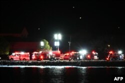 Машыны хуткай дапамогі і ратавальнікі зьбіраюцца ўздоўж ракі Патомак каля нацыянальнага аэрапорту Рэйгана пасьля авіякатастрофы