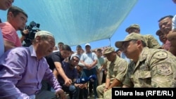 Исполняющий обязанности начальника штаба пограничного управления по Бейнеускому району Аскар Аяганов отвечает на вопросы  Бахыта Алтынбекова (слева), отца погибшего военнослужащего. Сарыагаш (Туркестанская область), 6 июня 2022 года