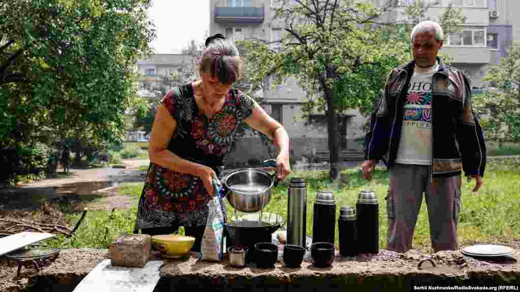 Місцева жителька розливає воду в термоси