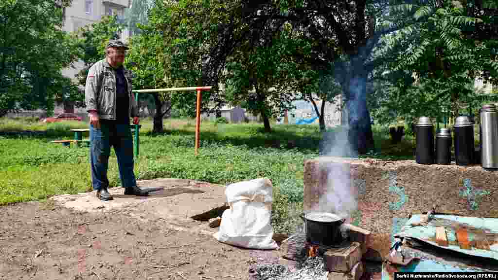 Місцевий житель готує їжу на відкритому вогні біля бомбосховища на одній з вулиць міста