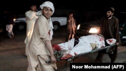 Men carry a wounded man on a stretcher outside a hospital following a car bomb in Lashkar Gah on March 23.