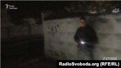 Чоловік у цивільному направляє пістолет на журналістів