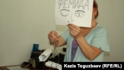 Активистка  движения "За справедливость" держит в руках весы, которые символизируют: коррупция перевесила законность на весах казахстанской Фемиды. Алматы, 27 августа 2014 года.     