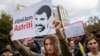 Protesters hold portraits of activist Astrit Dehari in Pristina on November 5.