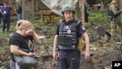 A woman cries as police officers inspect the site of the Russian missile attack that hit a recreation area, killing five people, including a pregnant woman, on the outskirts of Kharkiv on May 19.
