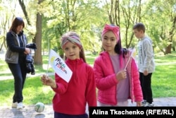 Діти тримають прапорці із назвою свого міста