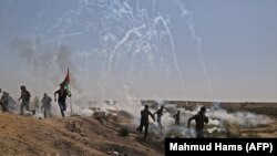 تظاهرکنندگان فلسطینی از گازهای اشک‌آوری که به سوی آنها شلیک شده است، می‌گریزند