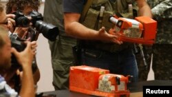 Окупований Донецьк, 22 липня 2014 року. На фотографії бойовики угруповання «ДНР», що визнане в Україні терористичним, передають малайзійським експертам чорні скриньки «Боїнга» рейсу MH-17, який був збитий російською зенітно-ракетною установкою «Бук»