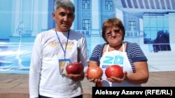 Садоводы Сапар Бекмагамбетов и Ольга Суздалева держат в руках яблоки - алматинский апорт. Алматы, 16 сентября 2012 года. Иллюстративное фото.     
