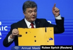 Президент України Петро Порошенко демонструє фрагмент пасажирського автобуса, який був знищений ракетним ударом російсько-сепаратистських сил на околиці Волновахи 13 січня 2015 року. Давос, 21 січня 2015 року