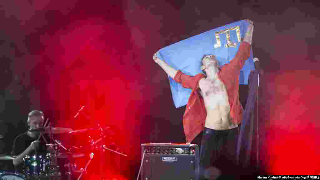 Святослав Вакарчук з прапором кримсько татарського народу під час концерту &laquo;Океану Ельзи&raquo; у Києві, 26 травня 2019 року