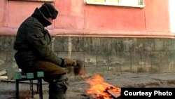 Житель города Приозерска обогревается на улице. Приозерск, январь 2011 года.  