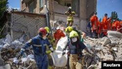 Рятувальники несуть тіло людини, знайдене під завалами на місці ураження житлового будинку внаслідок російського ракетного удару у Києві, Україна, 9 липня 2024 року