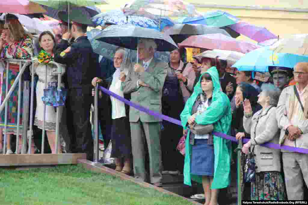 Люди під парасольками спостерігають за урочистостями