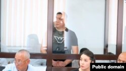 Абзал Шынасыл (за стеклом), единственный из обвиняемых, который дал согласие на видеосъемку своего лица. Он получил 23 года лишения свободы