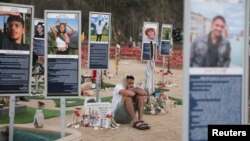 Мъж седи сред възпоменателни табели с жертви от музикалния фестивал "Нова" в Израел, където бяха убити и отвлечени стотици млади хора по време на атаката на Хамас преди две години, 7 октомври 2025 г.