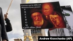 Під час акції представників іранської громади України проти російського та іранського режимів. Київ, 28 жовтня 2022 року На плакаті зображено очільника Росії Володимира Путіна, верховного лідера Ірану аятоллу Алі Хаменеї та Адольфа Гітлера