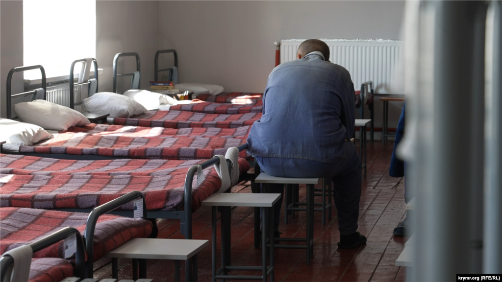 Житлова кімната в таборі для військовополонених. У житлових приміщеннях є двоповерхові та звичайні ліжка. У багатьох на тумбочках є книги, переважно російською. У таборі також є бібліотека