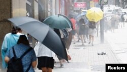 Люди ховаються під парасолями від розпиленого силовиками перцевого газу під час протесту проти закону про гімн, Гонконг, 27 травня 2020 року