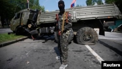 Пророссийский сепаратист стоит рядом с подорванным грузовиком у донецкого аэропорта. 29 мая 2014 года.