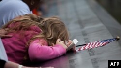 Жінка плаче над ім'ям коханої людини, вписаному на стіну меморіалу на місці Всесвітнього торговельного центру, Нью-Йорк, 11 вересня 2011 року
