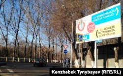 Жемқорлықпен күресуге үндейтін жарнама жанында тұрған ішкі істер әскерилері. Алматы, 21 наурыз 2015 жыл.