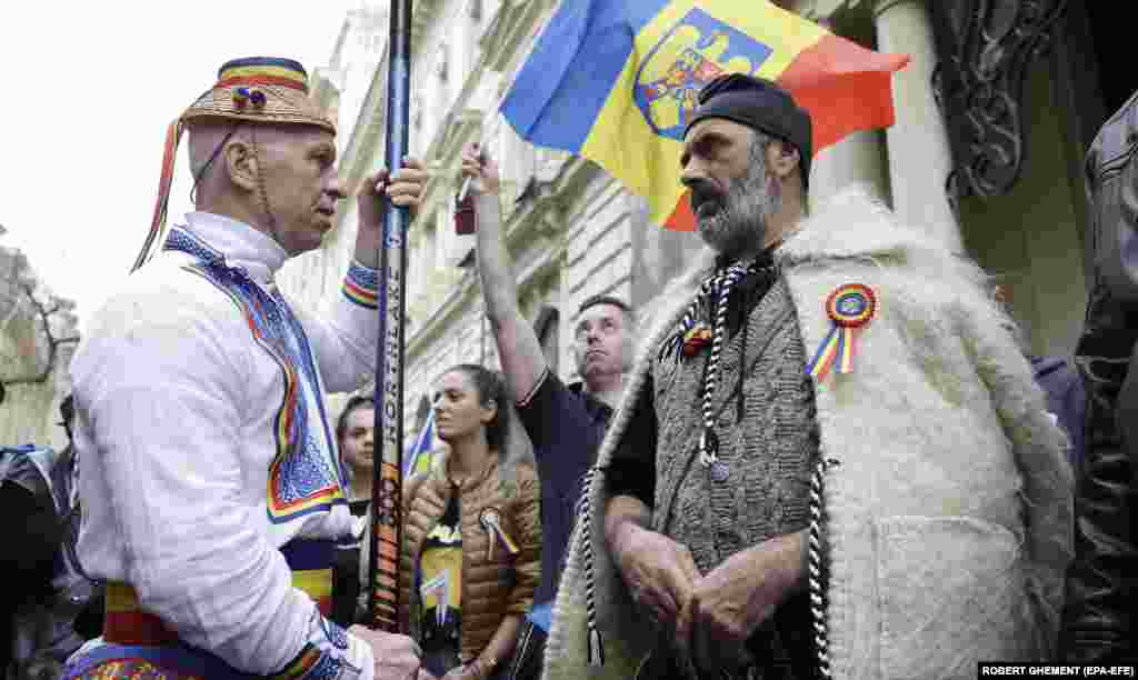 مردانی با لباس‌های سنتی داسیایی (سمت راست) و روستایی در تظاهرات ملی‌گرایان افراطی رومانی علیه لغو نتایج دور اول انتخابات ریاست‌جمهوری در بخارست.