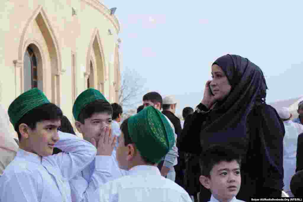 Хлопці в святковому національному вбранні, жінка традиційно в хіджабі