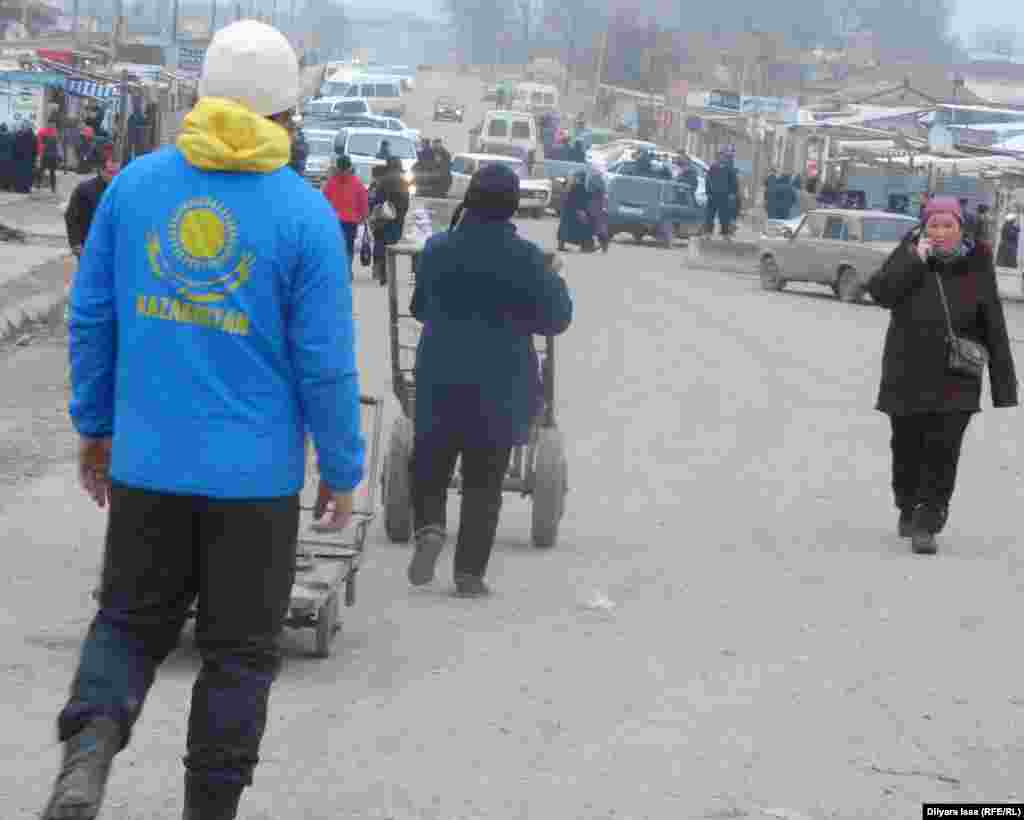 На казахстанской стороне поста &quot;Жибек жолы&quot; десятки человек предлагают свои услуги для переходящих границу. Одни предлагают перенести на тележках тяжелый груз через границу, другие продают еду и напитки, третьи меняют валюту. Есть и частники на своих машинах, которые могут довезти пассажиров до нужного им населенного пункта. &nbsp;