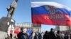 Ukraine -- A pro-Russian protester waves a Russian flag next to a statue of Vladimir Lenin during a rally in the centre of the eastern city of Donetsk, March 10, 2014