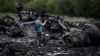 A journalist takes photographs at the site of the Malaysia Airlines Boeing 777 plane crash near the settlement of Hrabovo, in the Donetsk region, on July 18, one day after the crash, which killed all 298 people aboard.